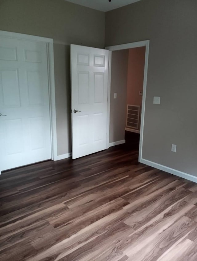 unfurnished bedroom with dark hardwood / wood-style flooring and a closet