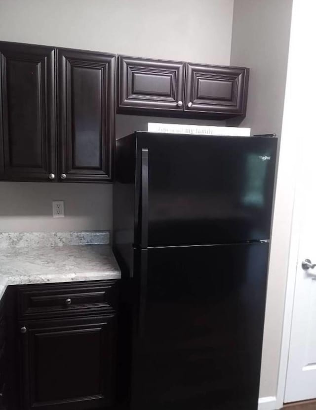 kitchen with dark brown cabinets and black fridge