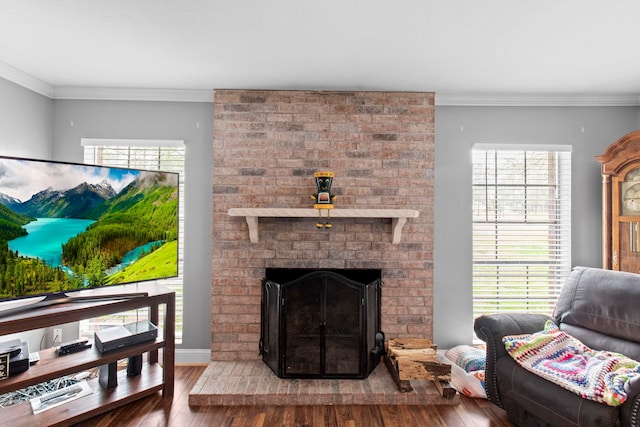 living room featuring a brick fireplace, wood finished floors, and crown molding