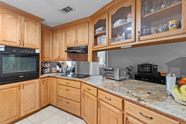 kitchen with visible vents, under cabinet range hood, a toaster, light tile patterned floors, and black appliances