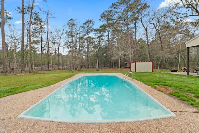 view of swimming pool featuring an outbuilding, a storage unit, and a yard