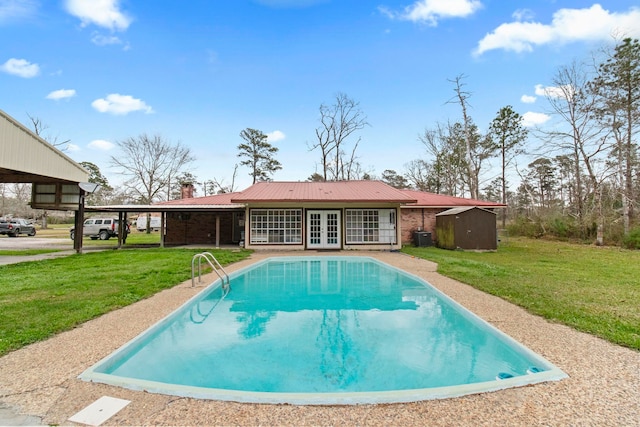 view of swimming pool featuring a yard and french doors