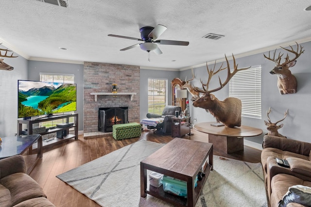 living area featuring visible vents, a brick fireplace, hardwood / wood-style floors, and ornamental molding