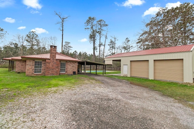 view of side of home featuring a chimney, an outdoor structure, a lawn, brick siding, and metal roof