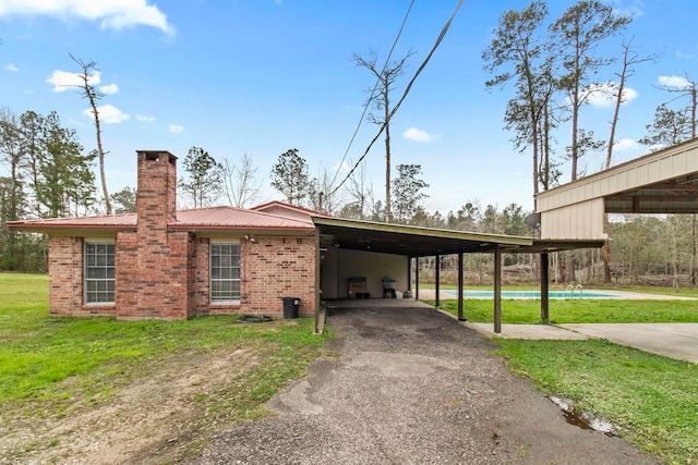 exterior space featuring aphalt driveway, an attached carport, metal roof, and brick siding