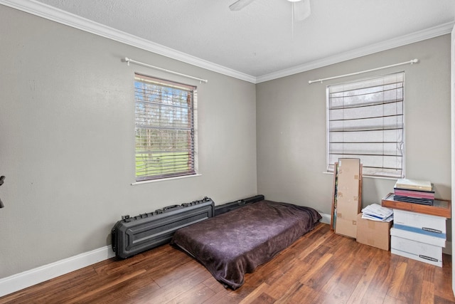 bedroom featuring ornamental molding, a textured ceiling, hardwood / wood-style floors, baseboards, and ceiling fan