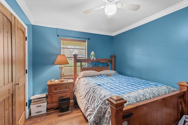 bedroom with a closet, crown molding, a ceiling fan, and wood finished floors