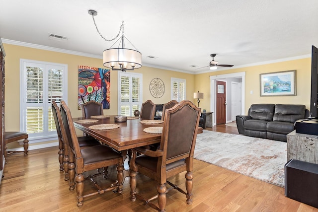 dining space featuring a healthy amount of sunlight, light wood-style flooring, and crown molding