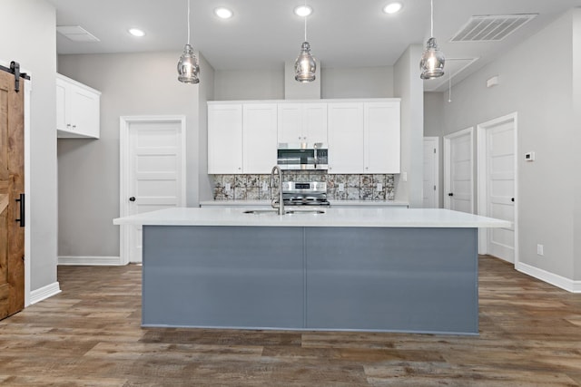 4450 W Brown St, Orange, TX 77630 - kitchen with appliances with stainless steel finishes, a sink, a barn door, a center island with sink, and decorative backsplash