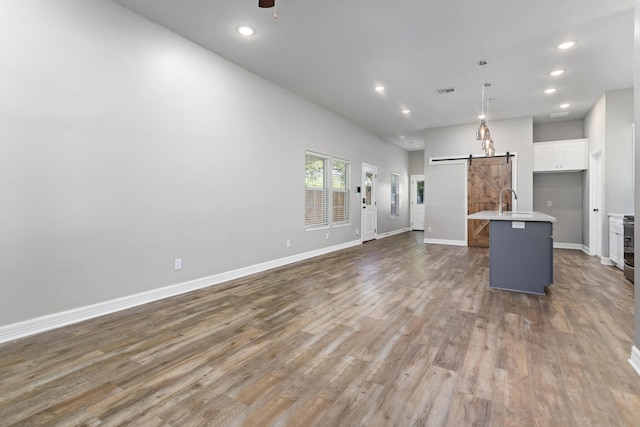 4450 W Brown St, Orange, TX 77630 - unfurnished living room featuring a barn door, recessed lighting, wood finished floors, ceiling fan, and baseboards