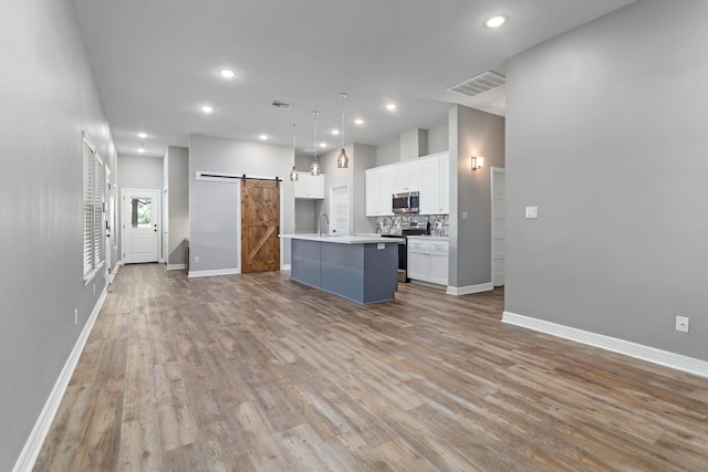 4450 W Brown St, Orange, TX 77630 - kitchen featuring appliances with stainless steel finishes, a barn door, white cabinetry, baseboards, and light wood finished floors