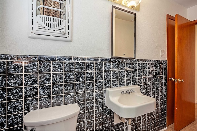 bathroom with sink, tile walls, and toilet