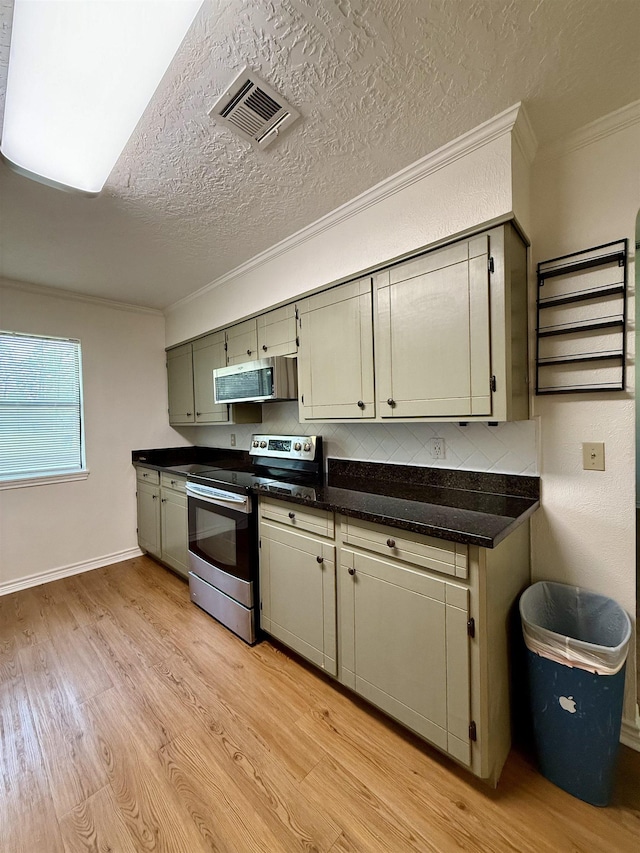 175 Princeton Pl, Vidor, TX 77662 - kitchen with stainless steel appliances, light wood finished floors, ornamental molding, dark countertops, and backsplash