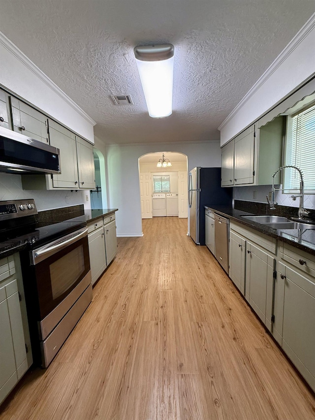 175 Princeton Pl, Vidor, TX 77662 - kitchen featuring stainless steel appliances, a sink, a textured ceiling, arched walkways, and dark countertops