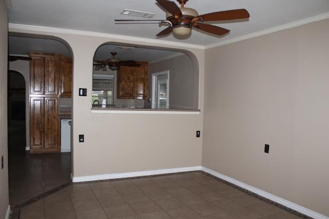 empty room featuring dark tile patterned flooring, ceiling fan, and crown molding