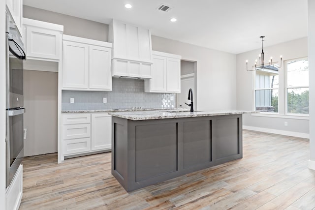 kitchen with visible vents, light wood-type flooring, a sink, backsplash, and white cabinets