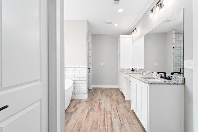 full bathroom with visible vents, double vanity, a stall shower, wood finished floors, and a soaking tub