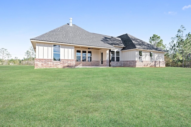 rear view of property featuring board and batten siding, a lawn, and brick siding