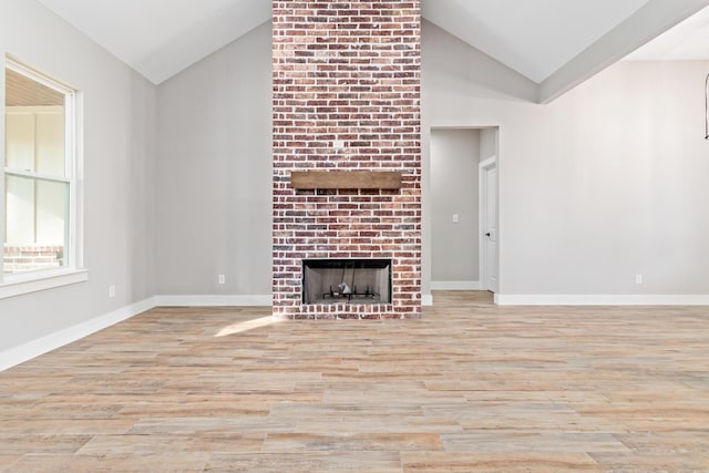 unfurnished living room featuring a fireplace, wood finished floors, baseboards, and vaulted ceiling