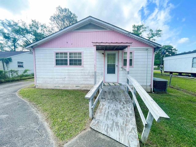 bungalow-style home featuring a front yard, central AC, and fence