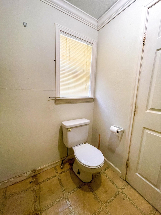 bathroom featuring ornamental molding, toilet, and baseboards