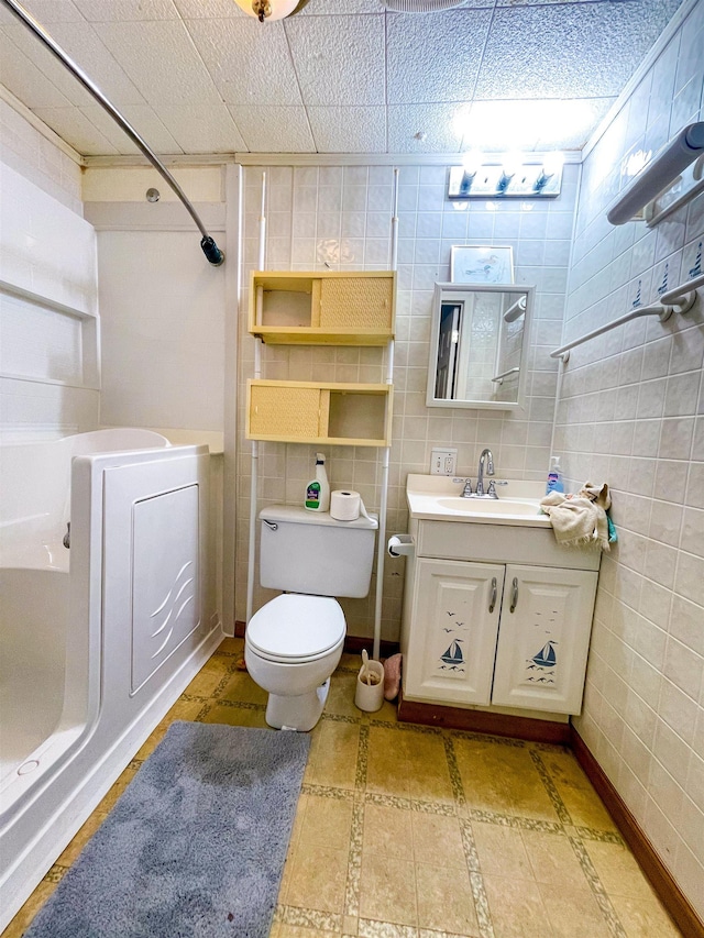 full bath with a shower, toilet, tile walls, vanity, and tile patterned flooring