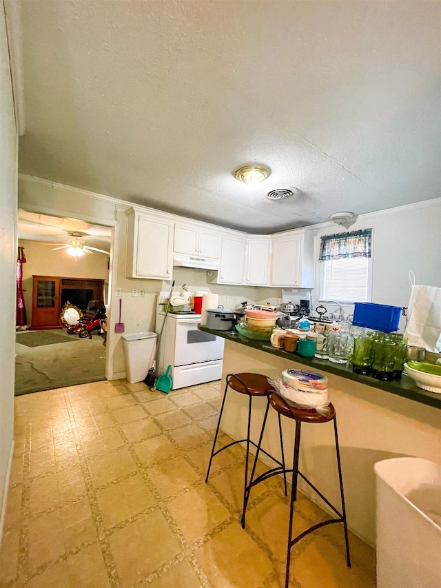 kitchen featuring a textured ceiling, white cabinets, under cabinet range hood, white electric range, and light floors