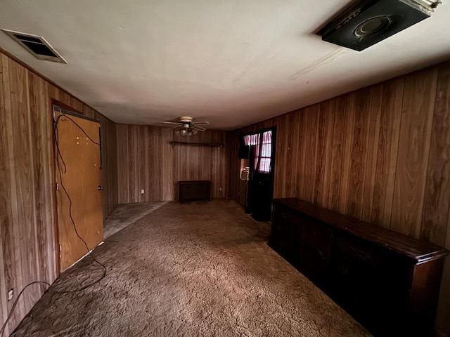 unfurnished living room featuring wooden walls, visible vents, and carpet flooring