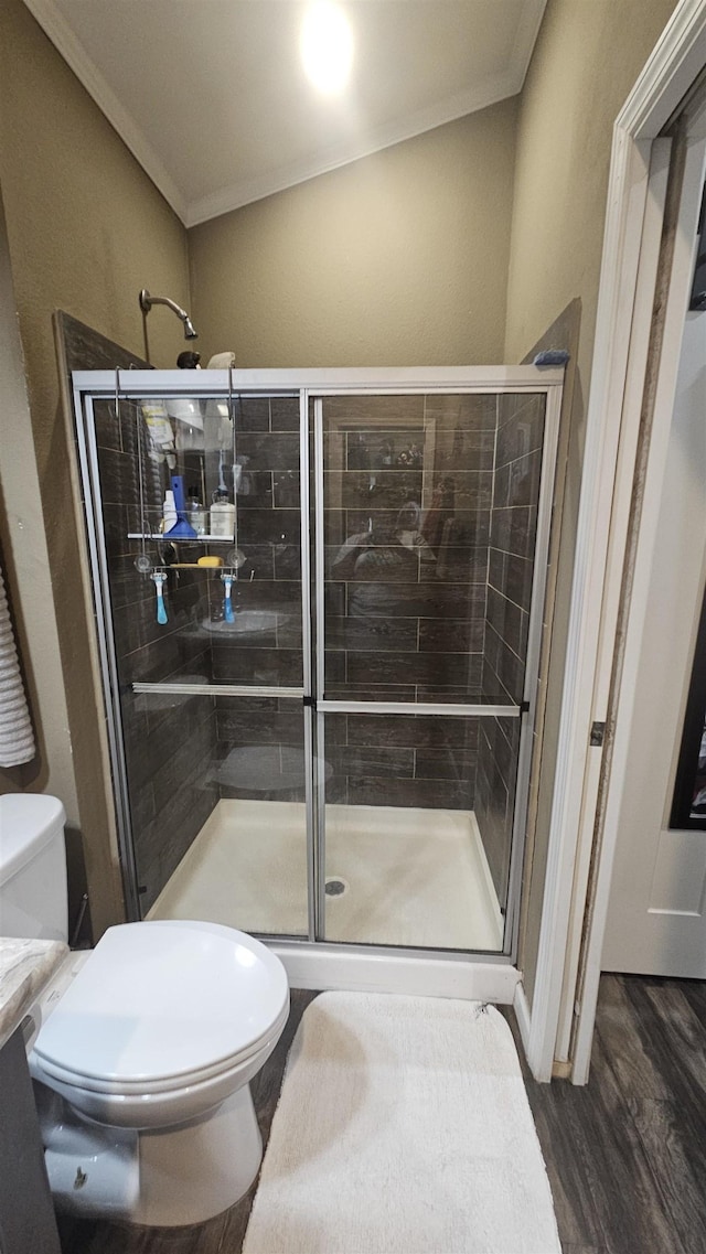 bathroom featuring wood-type flooring, toilet, a shower with shower door, and crown molding