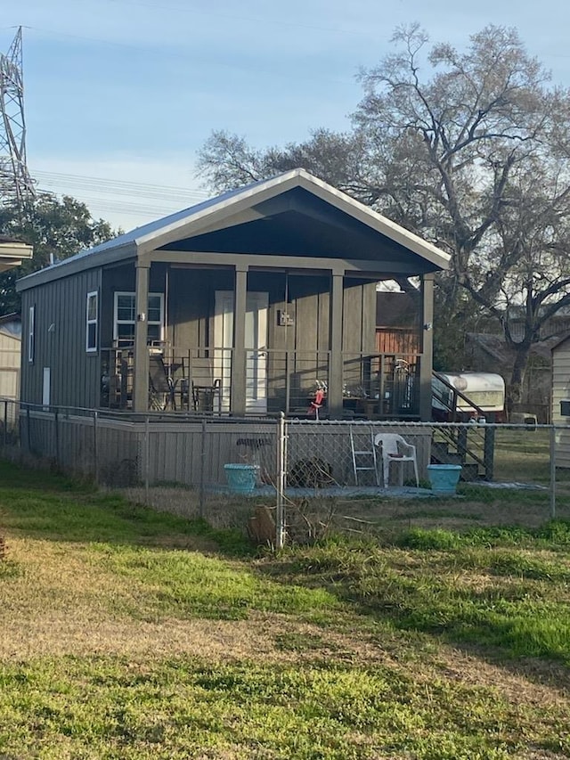 rear view of house featuring a lawn and covered porch