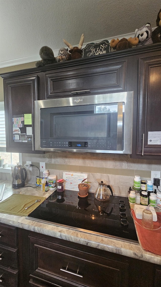 kitchen featuring backsplash, dark brown cabinetry, and black electric stovetop