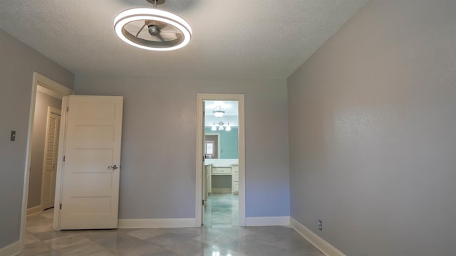 spare room with a textured ceiling and baseboards