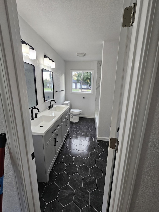 bathroom with walk in shower, vanity, a textured ceiling, and toilet