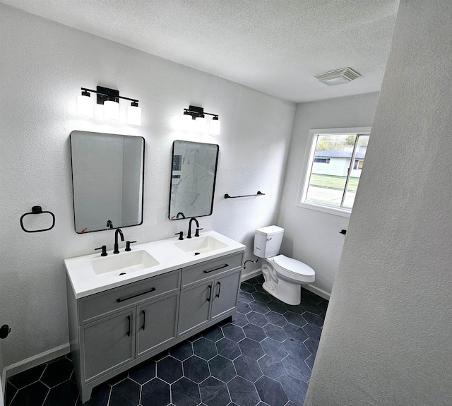 bathroom with tile patterned flooring, a textured ceiling, vanity, and toilet