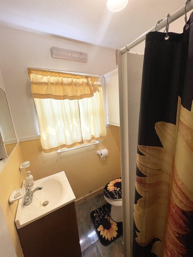 bathroom with a shower with curtain, vanity, tile walls, and toilet