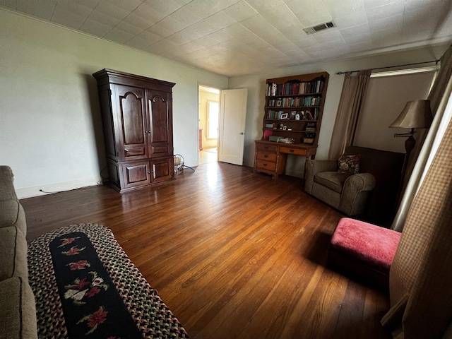 living area with wood finished floors, visible vents, and baseboards