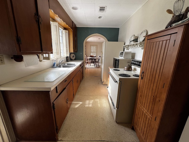 kitchen featuring white range with electric stovetop, arched walkways, light countertops, visible vents, and a sink