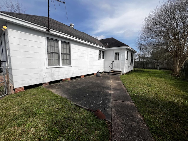 exterior space featuring entry steps, a patio, fence, a yard, and roof with shingles