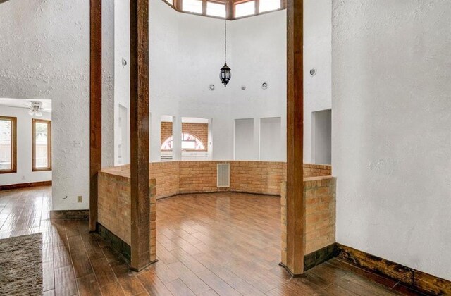 entrance foyer with ceiling fan, hardwood / wood-style floors, and a towering ceiling