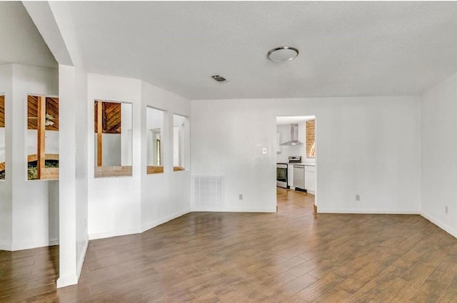 spare room featuring a textured ceiling and dark hardwood / wood-style flooring