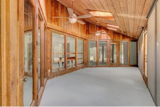 misc room with wooden ceiling, ceiling fan, wooden walls, concrete flooring, and vaulted ceiling with skylight