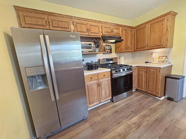 330 Avenue E Ave E, Port Neches, TX 77651 - kitchen with appliances with stainless steel finishes, ventilation hood, light wood-type flooring, light countertops, and brown cabinetry
