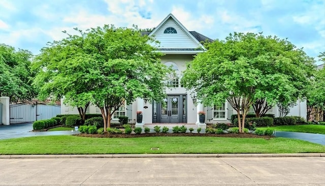 5065 Oakmont Dr, Beaumont, TX 77706 - view of front of house with french doors, a gate, a front lawn, and stucco siding