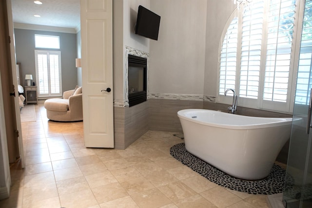 5065 Oakmont Dr, Beaumont, TX 77706 - full bath with a freestanding bath, crown molding, tile walls, a fireplace, and tile patterned flooring
