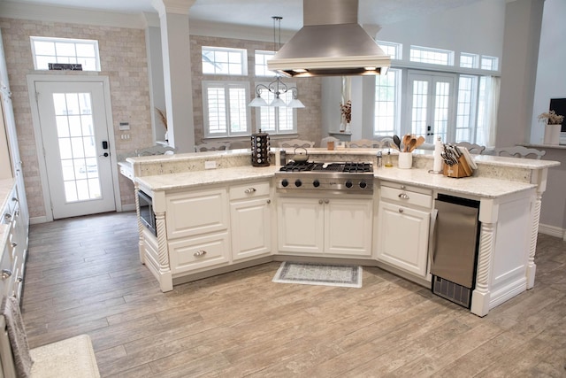 5065 Oakmont Dr, Beaumont, TX 77706 - kitchen with island exhaust hood, appliances with stainless steel finishes, ornamental molding, light wood-type flooring, and healthy amount of natural light