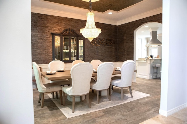 5065 Oakmont Dr, Beaumont, TX 77706 - dining space featuring a chandelier, wood finished floors, a raised ceiling, ornamental molding, and arched walkways