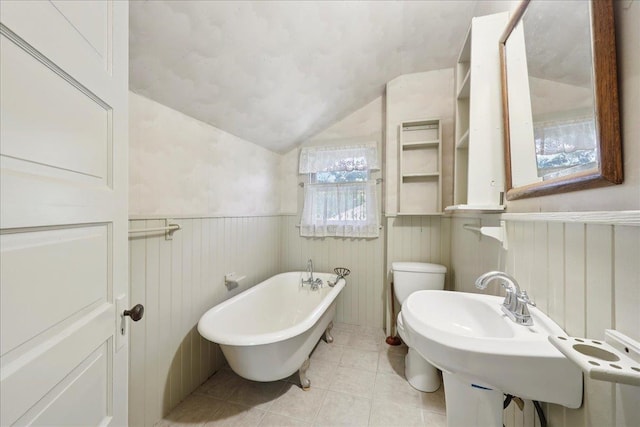 507 Orange Ave, Orange, TX 77630 - bathroom with lofted ceiling, a freestanding tub, wainscoting, and tile patterned flooring