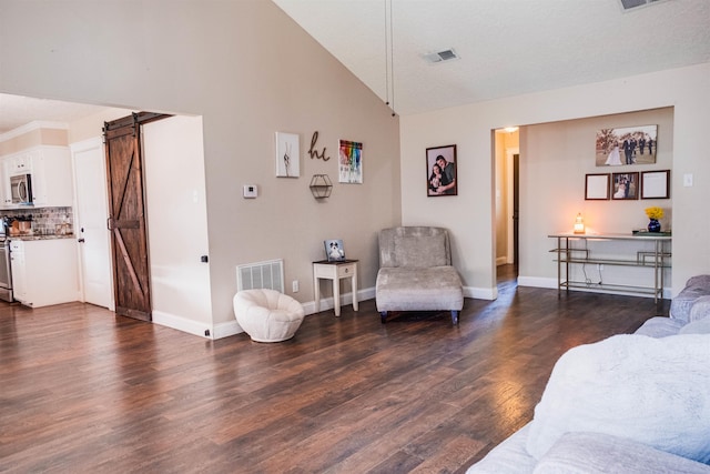 living room featuring dark wood-type flooring, a barn door, and high vaulted ceiling