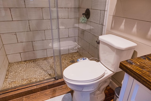 bathroom featuring hardwood / wood-style flooring, toilet, and a shower with shower door