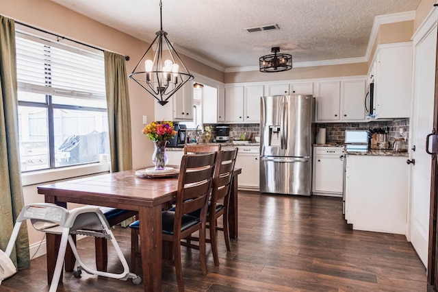 dining area with dark hardwood / wood-style floors, sink, ornamental molding, a notable chandelier, and a textured ceiling